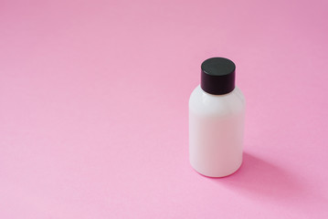 Cosmetic product bottle white with black cap for body skin care cosmetics or hair on pink background. side view with copy space, banner or template. The concept of beauty product        