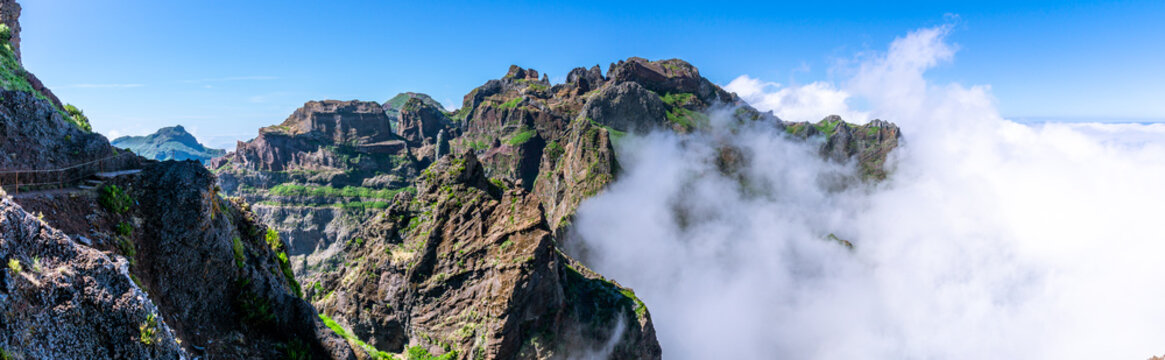 Panorama image of mountains with hiking trail hit by huge clouds and blue sky