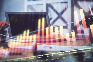 Stock market graph on background with desk and personal computer. Double exposure. Concept of financial analysis.