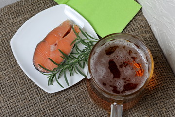 A glass of frothy beer and salmon steak with rosemary. View from above. Beer Festival.