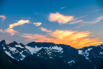 Alpenglow on clouds over a rugged mountain range in Mt. Rainier National Park.