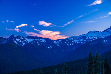 Alpenglow on clouds over a rugged mountain range in Mt. Rainier National Park.