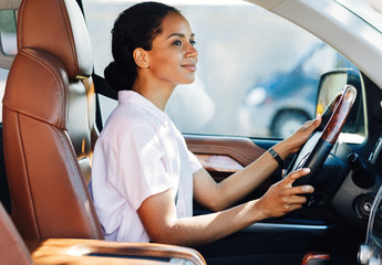 Confident young woman driving car. Side view of female holding a steering wheel.