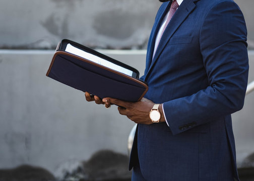 Midsection of man in suit holding notebook