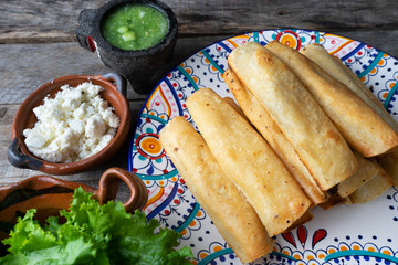 Mexican fried tacos also called "flautas" on wooden background