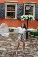 Concept of life modern woman in big city, playing with her umbrella. It's summer rain. Brunette...