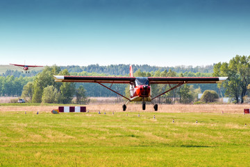 Landing of two red private planes one after another at a small airfield