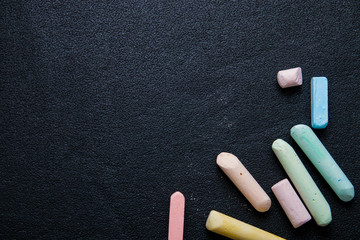 several colored crayons on a black background, chalk, draw on the asphalt with chalk, copy space, top view