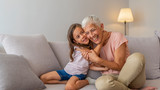 Happy senior woman hugging her beautiful grandchild at home. Portrait of grandmother and granddaughter. "My gran means the world to me". Little girl with grandmother
