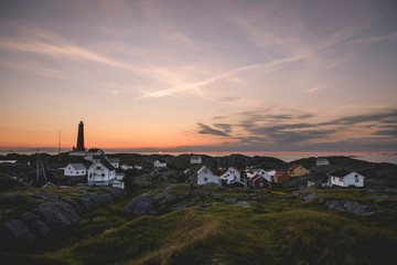 Fototapeta na wymiar Island village with lighthouse at sunset