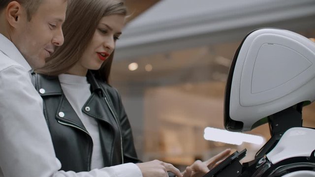 A man and a woman communicate with a cybernetic person smiling and laughing. Robot droid interacts with humans.