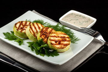 Concept for a healthy summer diet: baked zucchini with dill sauce