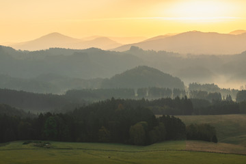 Hilly landscape during warm and bright sunrise. Very peaceful and pleasing scene. Forests and hills without any industry or buildings.