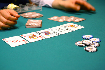On the poker table there is a combination of cards, tokens, croupier hands, a stack for tokens.