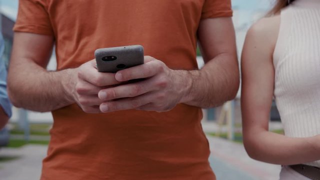 Close-up best friends standing in row holding and using modern mobile gadgets in the street. Mobile future generation, smartphone army.