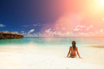 Fototapeta na wymiar Young fashion woman relax on the sunny beach. Happy lifestyle. White sand, blue sky and crystal sea of tropical beach. Vacation at Paradise. Ocean beach relax, travel to islands