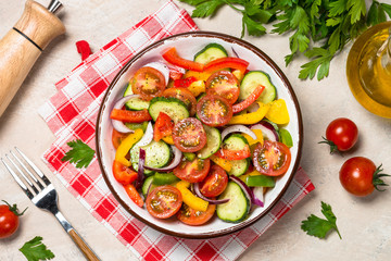 Summer fresh vegetable salad on light table top view.