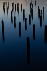 long exposure of wood pilings in blue ocean water at dusk