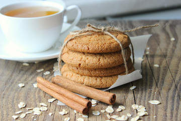 Homemade oatmeal cookies and a Cup of tea on an old wooden table, rustic style. Oatmeal and cinnamon sticks. Copy space.