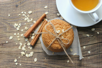 Homemade oatmeal cookies and a Cup of tea on an old wooden table, rustic style. Oatmeal and cinnamon sticks. Copy space.The view from the top.
