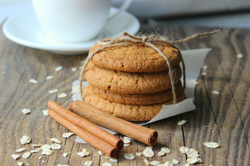 Homemade oatmeal cookies on an old wooden table, rustic style. Oatmeal and cinnamon sticks. Copy space.