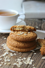 Homemade oatmeal cookies and a Cup of tea on an old wooden table, rustic style. Oatmeal and cinnamon sticks. Copy space.