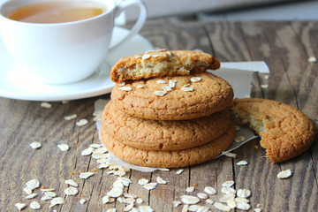 Homemade oatmeal cookies and a Cup of tea on an old wooden table, rustic style. Oatmeal and cinnamon sticks. Copy space.
