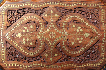 Beautiful wooden carved table top on the Indian market with floral patterns and metal inlay in Indian traditional crafts