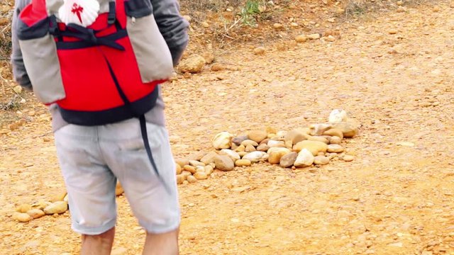 way of  st james to Compostela , pilgrim placing a stone on the arrow symbol , video hd footage