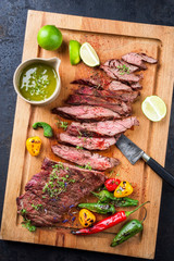 Modern design barbecue dry aged wagyu bavette de flanchet steak with chili and chimichurri sauce as top view on a wooden cutting board