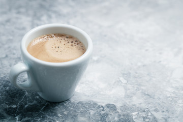 Cup of coffee on bright stone background. Copy space