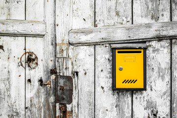 Old wooden gate with yellow mailbox. Vertical planks, background, textures
