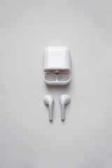 Glossy white wireless headphones with plastic container isolated on white background