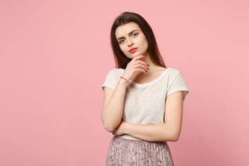 Obraz premium Pensive young woman in casual light clothes posing isolated on pink background, studio portrait. People sincere emotions lifestyle concept. Mock up copy space. Looking camera put hand prop up on chin.
