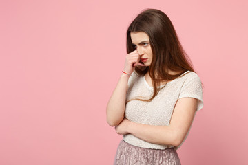 Obraz premium Displeased young woman in casual light clothes posing isolated on pink background studio portrait. People sincere emotions lifestyle concept. Mock up copy space. Looking aside covering nose with hand.
