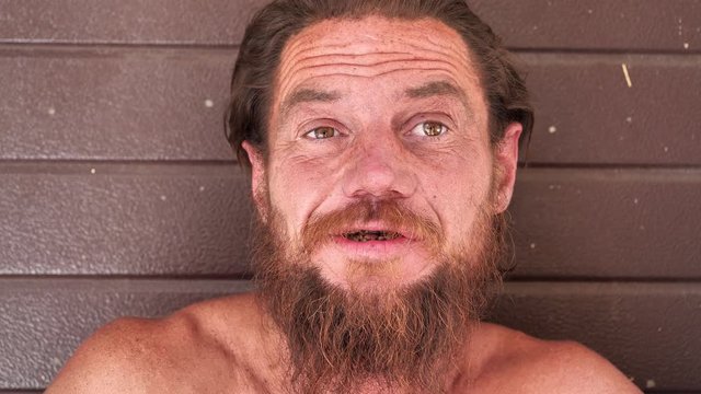 Homeless man looks at the camera and talks. Down-and-out person on the street. Real person with no fixed abode