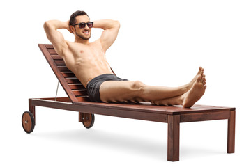 Handsome young man sunbathing on a lounge chair