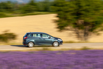Fototapeta na wymiar Motion blur image of the car which travells through countryside with lavender fields in Provence, France