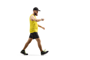 Bearded guy in sportswear walking and looking at his smartwatch