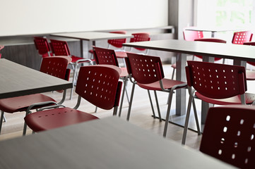 Empty dining room with red chairs and gray tables.