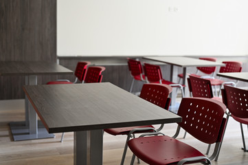 Empty dining room with red chairs and gray tables.