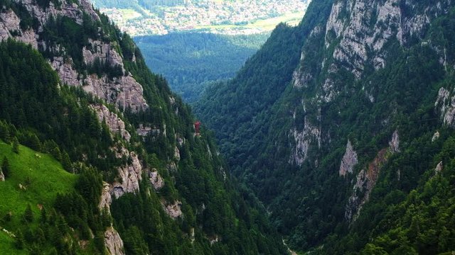 Cinematic shot of the fir, Bucegi mountains, Busteni city and skyline in Romania