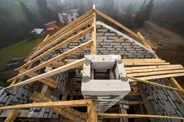 Top view of roof frame from wooden lumber beams and planks on walls made of hollow foam insulation blocks. Building, roofing, construction and renovation concept.