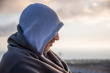 Man in a hood thinking at the sunset