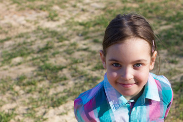 A cute little girl is standing in a field.