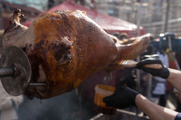 Traditional roasted shank ham cooking on charcoal spit roaster