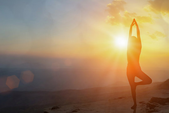 Young Women Meditate While Doing Yoga Meditation, Spiritual Mental Health Practice With Silhouette Of Lotus Pose Having Peaceful Mind Relaxation On Mountain Outdoor With Sunset Golden Heavenly.