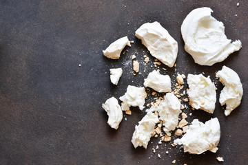 Broken meringues on a dark stone background.