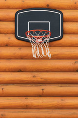 Basketball basket attached to an orange log wall. Outdoor play, alternative to the gym