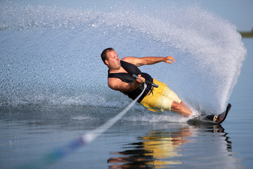 A man carving a turn on a slalom waterski.
